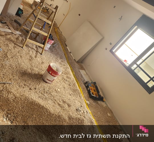 חדר בבנייה עם סולם, דלי וכלי עבודה על הרצפה